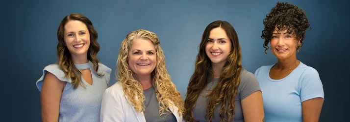 Chiropractic team members Candice, Joy McClenny, Caleigh, and Kim standing together.
